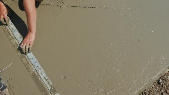 The builder levels the liquid concrete, makes a flat blind area