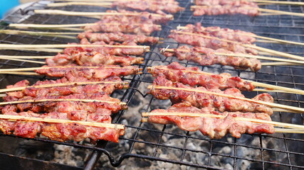 Pork skewers grilled over charcoal. Delicious Thai street food BBQ pork slices in the local market - Asian style. Selective focus