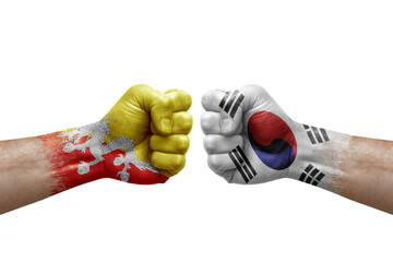 Two hands punch to each others on white background. Country flags painted fists, conflict crisis concept between bhutan and south korea