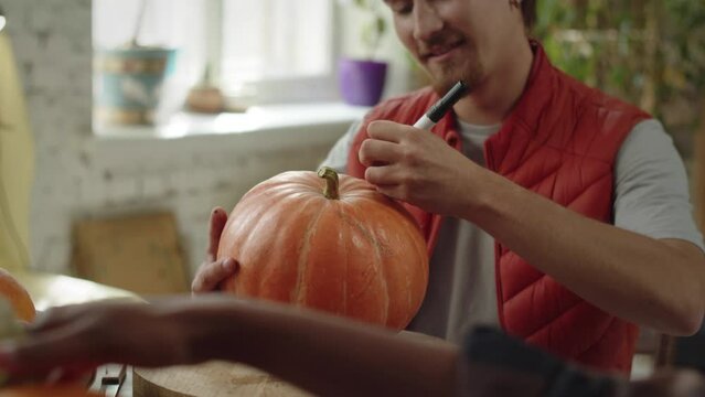A young man is drawing neatly on the pumpkin