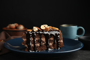 Piece of tasty homemade chocolate cake with nuts on black table, closeup. Space for text