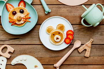 Creative meal for a child, pancake with strawberry, funny food over wooden background. Top view, flat lay