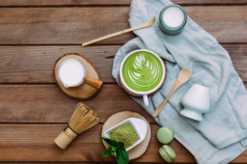 Green matcha tea in a white cup, tea powder and wooden spoon. Healthy drink. Top view, flat lay.