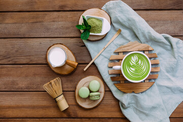 Fototapeta na wymiar Green matcha tea in a white cup, tea powder and wooden spoon. Healthy drink. Top view, flat lay.