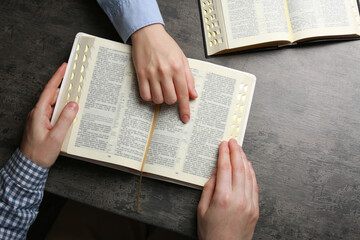 Humble couple reading Bibles at grey table together, top view