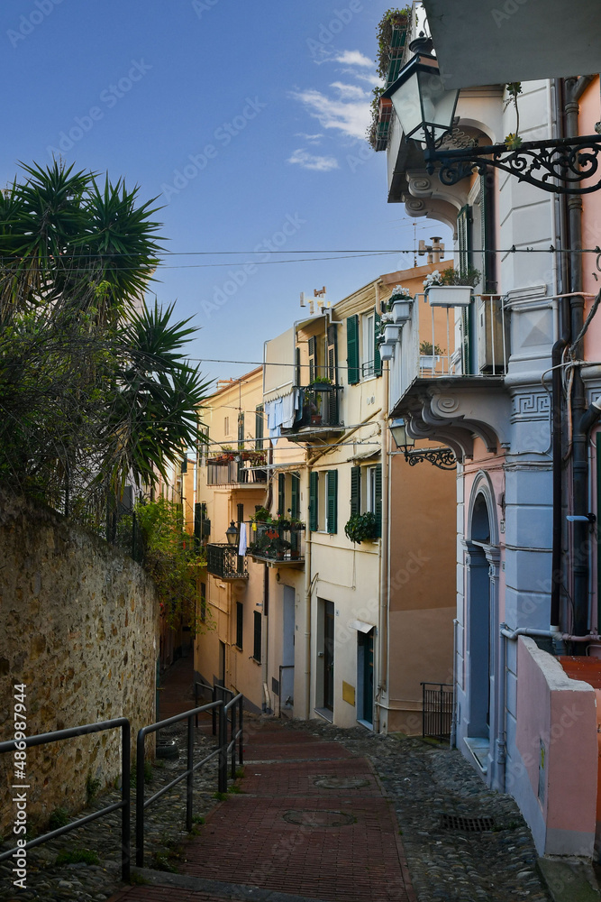 Wall mural A narrow uphill alley in the old town of Sanremo with the typical colored houses, Imperia, Liguria, Italy