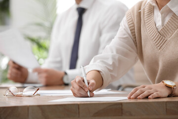 Woman signing contract at table in office, closeup.