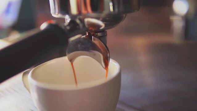 4k, espresso coffee is pouring from the coffee machine into a white cup, slow motion