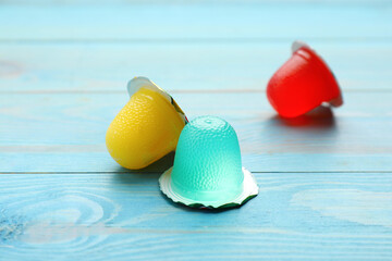 Fototapeta na wymiar Tasty bright jelly cups on light blue wooden table