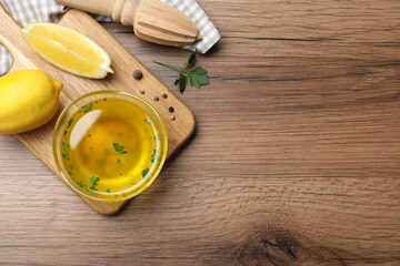 Bowl of lemon sauce and ingredients on wooden table, flat lay with space for text. Delicious salad dressing