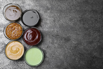 Many different sauces on grey table, flat lay. Space for text