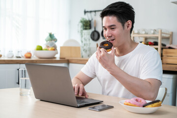 Asian business man eating unhealthy junk food while working from home. 