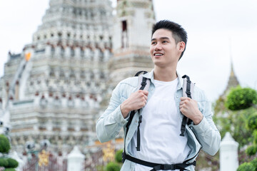 Asian attractive man backpacker walk around Buddha temple in Thailand. 