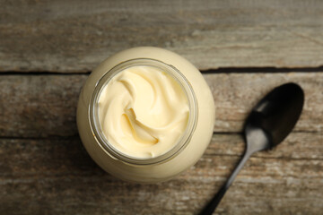 Jar of delicious mayonnaise and spoon on wooden table, flat lay