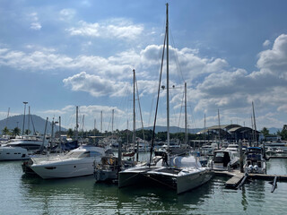 Sea harbor. Yacht club. Boats moored at the bay. Beautiful clouds. High masts of sailboats are directed to the sky. Yacht maintenance personnel, staff, navigation season. Luxury yachts, marina. Summer