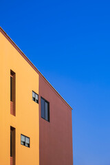 Side view of various fixing glass windows on orange and brown wall of modern house against blue clear sky in minimal style and vertical frame 