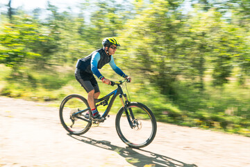 Obraz premium Panning photo of a cyclist racing down a country road