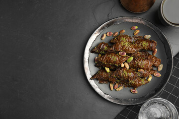 Delicious baklava with pistachio nuts on black table, flat lay. Space for text