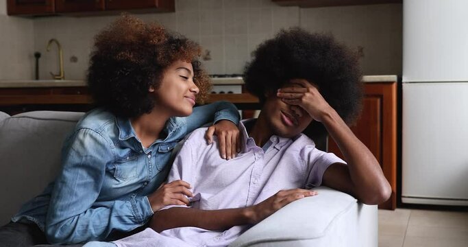 Cute tender African teenage girl admit her fault, try to make peace, apologizes, ask forgiveness after quarrel touch boyfriend calms him. Forgive me, saying sorry, excusing, romantic relations concept