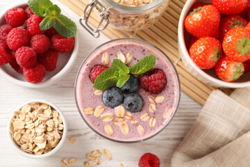 Flat lay composition with tasty oatmeal smoothie and berries on white wooden table