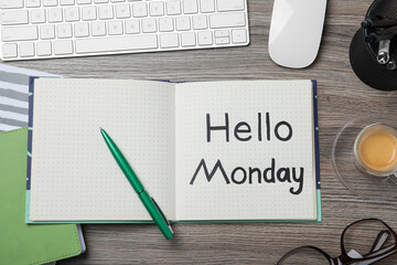 Message Hello Monday written in notebook, computer keyboard and cup of coffee on wooden desk, flat lay