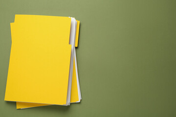 Yellow files with documents on olive background, top view. Space for text