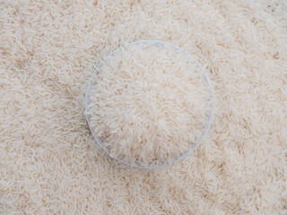 Close up top view rice in a white bowl and scattered near on wooden table with copy space for text and design