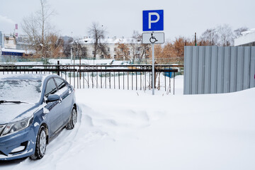 Snow-covered parking space. Parking for the disabled. Road parking sign for the disabled. Special parking place