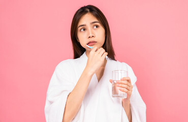 Asian woman wearing braces with brushing teeth and holding water glass, towel on the shoulder on pink background, Concept oral hygiene and health care.