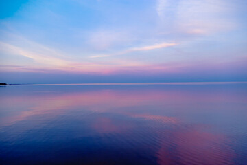 Beautiful sunset on sea, pastel colors and reflections on water, calm nature landscape with colorful clouds