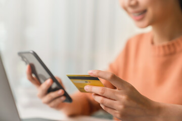 Close-up of hand holding credit card and using smartphone with online payment for shopping.