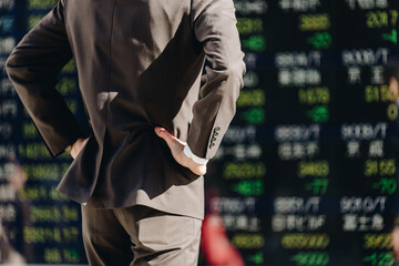 株価ボードを見る男性（ボディパーツ）