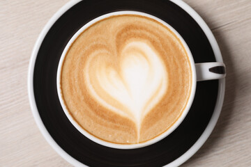 Cup of aromatic coffee on wooden table, top view