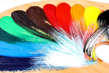 Pallette with colorful acrylic paint on white background, closeup view