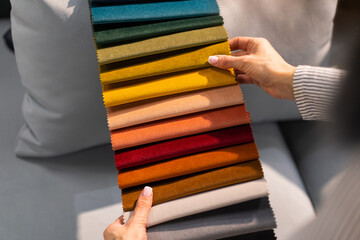 The woman chooses the fabric on the sofa. A young women looks at tissue samples. Selects the color of the sofa. Textile industry background. Tissue catalog