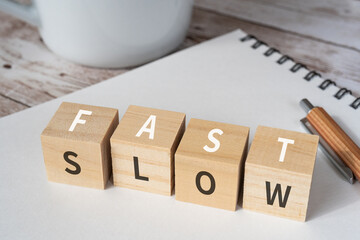 「FAST」「SLOW」と書かれた積み木、ペン、ノート、コーヒーカップ