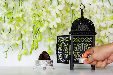 Candle puts in lantern with dates fruit that have orchid flower on white background for the Muslim...