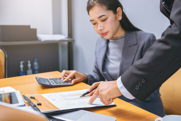 Woman accountant working on desk using calculator for calculate and checking finance report,...