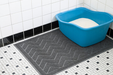 Black cat litter rubber mat on vintage bathroom floor with blue litter box in corner