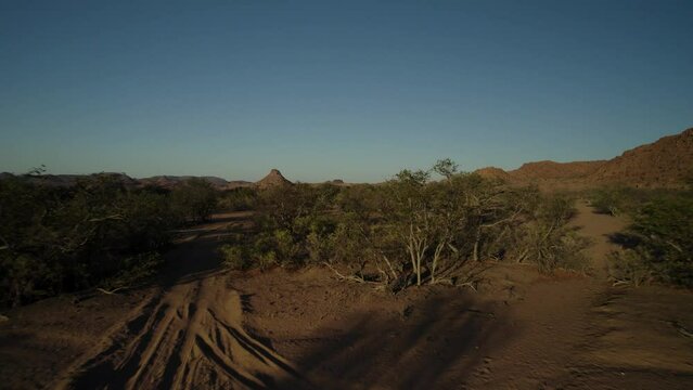 Low drone fly over shot of 4x4 vehicle on sandy dirt track in remote Namibia