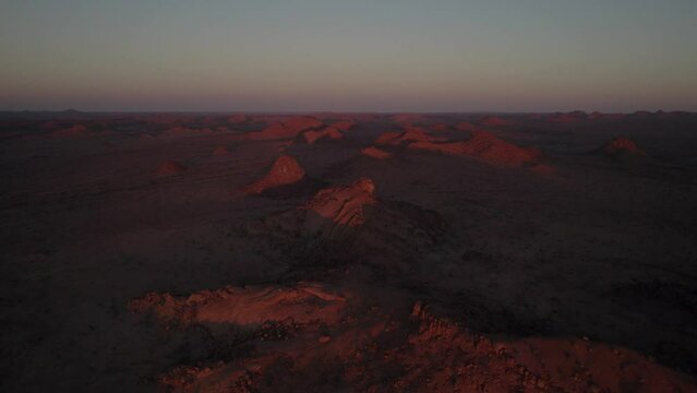 Drought stricken desert landscape glows red at sunset in Namibia; aerial