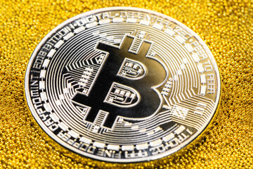 Silver bitcoin on yellow gold placer surface. Crypto currency. Bitcoin mining concept