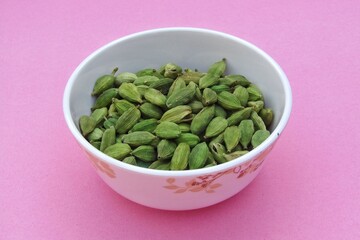 Cardamom in a bowl on pink background 