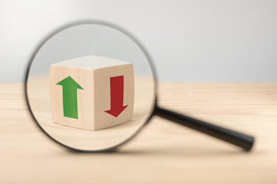 economic growth and decline analysis. Magnifying glass and wooden cube with green and red arrow. Business analysis concept, dynamics of growth and decline of indicators. Searching of decisions