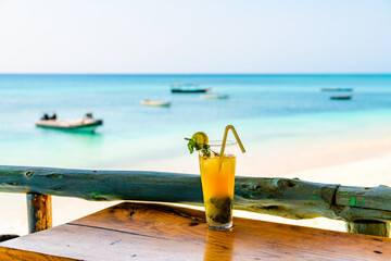 Glass of orange mojito cocktail. Ocean at the background