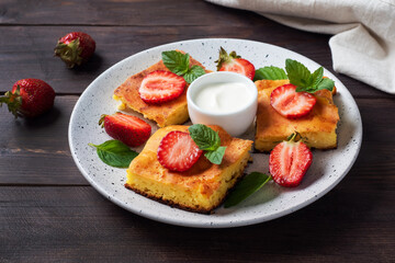 Cottage cheese casserole with strawberries and mint. Delicious homemade dessert made of curd and fresh berries with cream. dark wooden background, copy space.