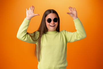 Funny caucasian teen girl in eyeglasses isolated on orange background