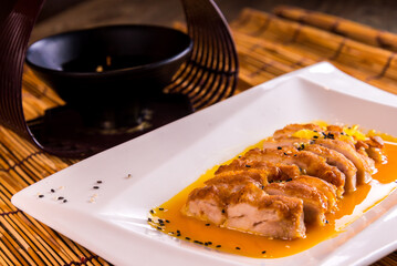 deep fried crispy chicken breast cutlet chop with yellow sour lemon sauce in plate on bamboo wood table asian cafe cuisine Chinese restaurant banquet halal food menu