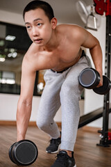 Fototapeta na wymiar Training gym concept a young adult using his muscular strong arm lifting a dumbbell upward and downward in the gym