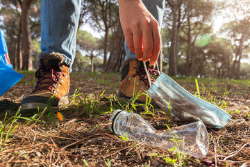 Close up of unrecognisable woman picking up trash to clean the forest.